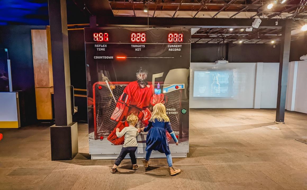 Young kids test out their goalie reflexes at an interactive station at Hockey: Faster Than Ever at Seattle's Pacific Science Center